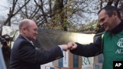 U.S. Sen. Chris Coons, left, greets a volunteer while visiting a United States Agency for International Development distribution center in Kyiv, Ukraine, Nov. 3, 2022. He and fellow U.S. Sen. Rob Portman promised continued humanitarian support for Ukrainians ahead of winter.