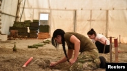Una mujer participa en un entrenamiento sobre la remoción de minas terrestres y otras municiones sin detonar, preparado para un grupo de ucranianos, incluidos civiles y oficiales del ejército, en medio de la invasión rusa de Ucrania en Peja, Kosovo, el 31 de mayo de 2022.