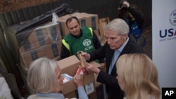 U.S. Sen. Rob Portman, right, talks with people during a visit to a distribution center of United States Agency for International Development in Kyiv, Ukraine, Nov. 3, 2022.