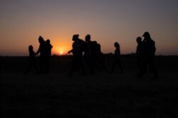 Porodice migranata iz Hondurasa i Salvadora koračaju prema graničnom zidu nakon što su splavom u Penitasu u Texasu iz Meksika prešle rijeku Rio Grande.