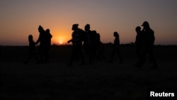 The sun rises as asylum-seeking migrant families from Honduras and El Salvador walk towards the border wall after crossing the Rio Grande River into the United States from Mexico on a raft, in Penitas, Texas on Mar 26, 2021. (REUTERS/Adrees Latif)