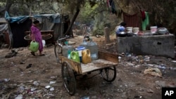 A woman carries buckets to fetch water from a public tap in a slum area in New Delhi, India, Jan. 17, 2016. The wealthiest 62 people own as much as half the world's population, as the super-rich have grown richer and the poor poorer, according to international charity Oxfam.