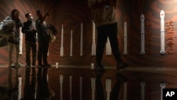 FILE - Visitors to an exhibition about China&#39;s space program stand near a depiction of the development of Chinese rockets, in Beijing on Dec. 28, 2023.