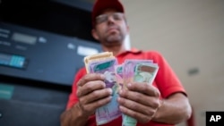 En esta foto de octubre de 2019, Orlando Godoy cuenta sus billetes de bolívares, la moneda local, en San Antonio de los Altos, en las afueras de Caracas, Venezuela.