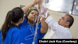 A Senior Clinical Nurse Specialist, Chakri Jack Kua (R) and his co-worker take care of a patient at South County Hospital, Rhode Island