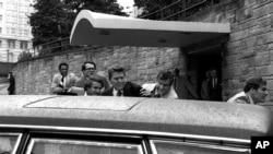 FILE - In this March 30, 1981, photo, U.S. president Ronald Reagan, center, is shown being shoved into his limousine by secret service agents after being shot outside a Washington hotel.