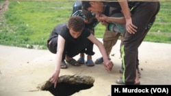 Children hold their noses as the examine the hole in one roof where a poisonous bomb hit more than a week ago, sending a woman and five children to the hospital in eastern Mosul, Iraq, March. 8, 2017. 
