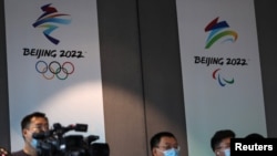 Reporters are seen in front of the Beijing 2022 Winter Olympic and Paralympic Games signs during a news conference on the construction progress of the sports event venues, at the headquarters of the Beijing Organising Committee, in Beijing, China July 30…