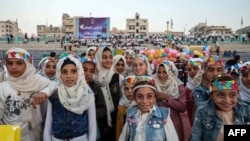 Girls pose on the pitch during the opening ceremony of the "Camps World Cup" at the newly-reopened Idlib Municipal Stadium in the rebel-held northwestern Syrian city on Nov. 19, 2022.