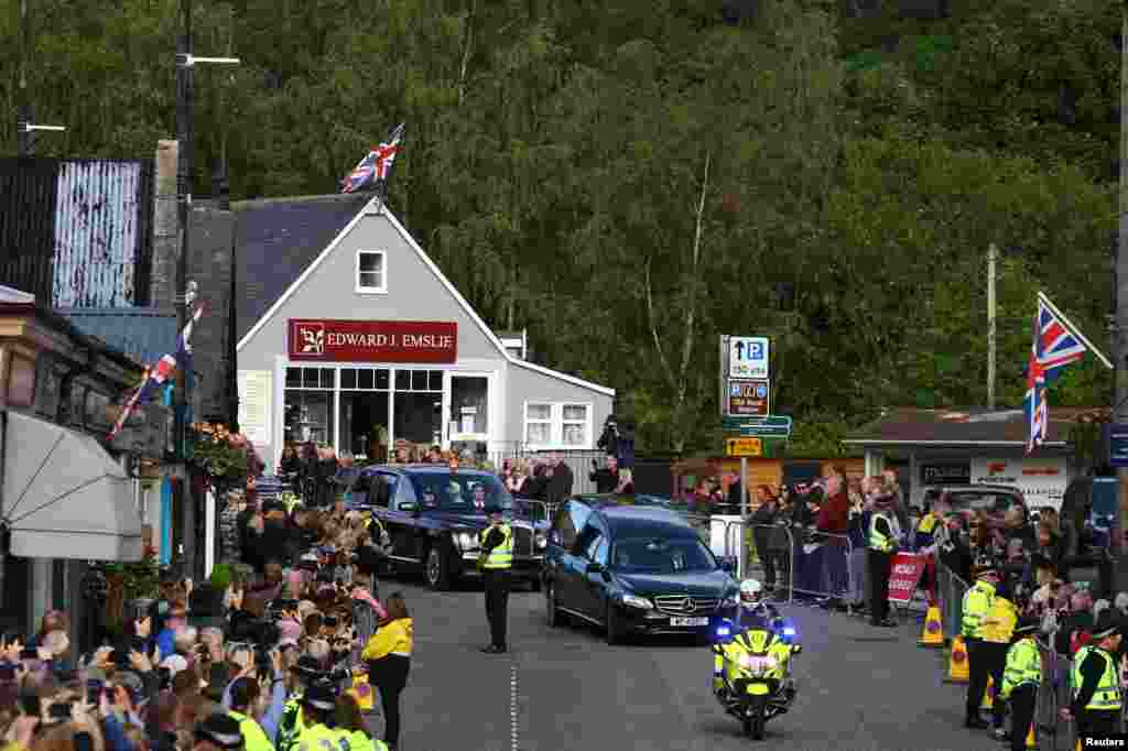 People line the street as the hearse carrying the coffin of Britain's Queen Elizabeth passes through the village of Ballater, near Balmoral, Sept. 11, 2022.