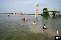 Internally displaced people wade through floodwaters to return home after heavy monsoon rains in Dadu district, Sindh province, Pakistan, Sept. 7, 2022.