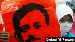 Seorang aktivis memegang poster aktivis hak asasi manusia Munir Thalib, yang meninggal dalam penerbangan Garuda Indonesia ke Amsterdam tahun lalu, di depan istana presiden di Jakarta pada 8 Desember 2005. (Foto: REUTERS/Dadang Tri)