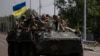 FILE - Ukrainian servicemen ride atop of an armored vehicle on a road in Donetsk region, eastern Ukraine, Aug. 28, 2022. 
