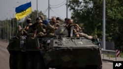 FILE - Ukrainian servicemen ride atop of an armored vehicle on a road in Donetsk region, eastern Ukraine, Aug. 28, 2022. 