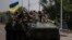 FILE - Ukrainian servicemen ride atop of an armored vehicle on a road in Donetsk region, eastern Ukraine, Aug. 28, 2022. 