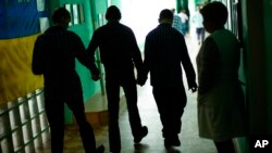 FILE - Residents walk along a corridor after lunch time in a facility for people with mental and physical disabilities in the village of Tavriiske, Ukraine, May 10, 2022. 