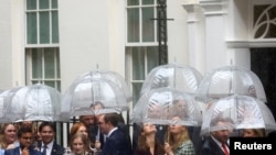 Supporters of new British Prime Minister Liz Truss wait amid rainfall for her arrival at Downing Street, in London, Britain Sept. 6, 2022.