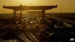 FILE - Shipping containers are offloaded at a BNSF Railway intermodal facility as the sun sets in Edgerton, Kan, Dec. 20, 2019.