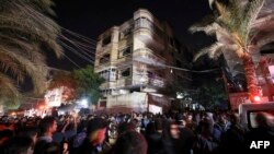 Warga Palestina berkumpul saat petugas pemadam kebakaran berusaha memadamkan api yang berkobar di salah satu gedung apartemen di kamp pengungsi Jabaliya di Jalur Gaza utara, Kamis 17 November 2022.