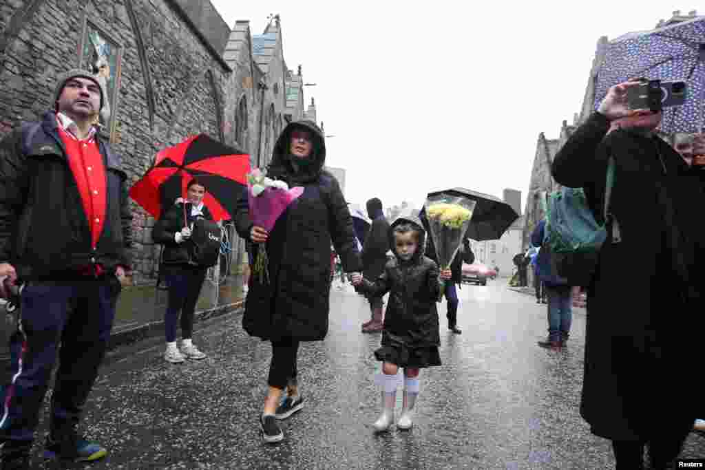 People carry flowers near the Palace of Holyroodhouse in Edinburgh, Scotland, Sept. 8, 2022.