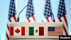 FILE - The flags of Canada, Mexico and the U.S. are seen on a lectern before a joint news conference on the closing of the seventh round of NAFTA talks in Mexico City, Mexico, March 5, 2018. 