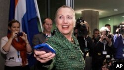 FILE - In this Dec. 8, 2011, file-pool photo, then-Secretary of State Hillary Rodham Clinton hands off her mobile phone after arriving for a meeting in The Hague, Netherlands.
