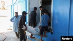 People carry the body of a migrant, whose boat sank in the sea, after the Libyan Coast Guards took them out from the Mediterranean Sea, in Garaboli, Libya, April 25, 2023. 