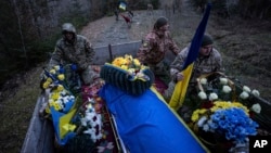 Ukrainian servicemen travel with the coffin of their comrade Vasyl Medviychuk during a funeral ceremony in Krasnyk village, Ukraine, Dec. 28, 2023.
