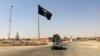 FILE - A vehicle passes by a flag of the Islamic State group in central Rawah, 281 kilometers northwest of Baghdad, Iraq. 