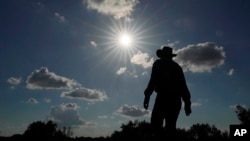 FILE - Kayak and canoe outfitter Jessie Fuentes walks along the Rio Grande under a warm sun, July 6, 2023. As the heat breaks records, weakening and sickening people, dire heat waves inspire effective efforts to prevent heat illness. 
