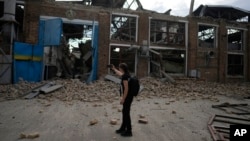 FILE - A journalist takes a photo of a railway service facility hit by a Russian missile strike in Kyiv, Ukraine, June 5, 2022. 