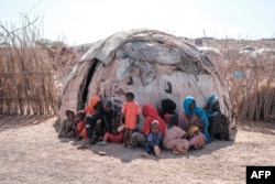 Perempuan dan anak-anak duduk di samping gubuk di kamp pengungsi Farburo di desa Adlale, dekat kota Gode, Ethiopia, 11 Januari 2023. (EDUARDO SOTERAS/AFP)