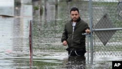 Francisco Lopez stands near the flooded parking lot of his apartment building, June 13, 2024, in Hallandale, Fla. 