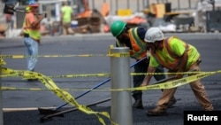 FILE - Workers spread hot asphalt on a road, after New York City issued an excessive heat warning, during hot weather in lower Manhattan in New York City, New York, July 27, 2023.