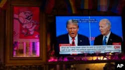 FILE - Presiden Joe Biden (kanan) dan calon presiden dari Partai Republik mantan Presiden Donald Trump (kiri), ditayangkan di layar televisi Tillie's Lounge, Cincinnati, saat berlangsungnya debat presiden, Kamis, 27 Juni 2024. (AP/Carolyn Kaster)