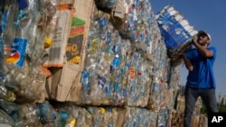 FILE - Worker carries compressed plastic bottles from the Nile to build Plastic Pyramid, in Cairo, Egypt, Sept. 15, 2022, to raise awareness on plastic pollution in the Nile.