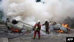 Firefighters extinguish burning cars on a street as clashes erupted at the end of a commemoration march for a teenage driver shot dead by a policeman, in the Parisian suburb of Nanterre, France, June 29, 2023.