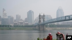 Seseorang duduk di dekat Sungai Ohio saat asap dari kebakaran hutan terlihat di pusat kota Cincinnati, Rabu, 28 Juni 2023. (AP/Joshua A. Bickel)