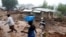 People walk past homes damaged by Cyclone Freddy in Chilobwe, Malawi, March 17, 2023.