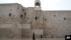 A priest walks by the Church of the Nativity, traditionally believed to be the birthplace of Jesus, on Christmas Eve, in the West Bank city of Bethlehem, Dec. 24, 2023. 