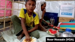 A Rohingya refugee child eats at Balukhali refugee camp, Cox’s Bazar, March 13, 2023. His grandmother eats watermelon.
