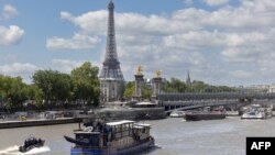 A Paris police boat (bottom left) makes its way past a cruise boat along the Seine in Paris on July 4, 2024. 