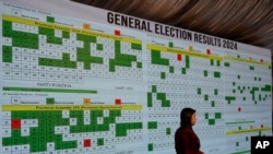 FILE - A TV crew member prepares in front of a screen showing the results of country's parliamentary elections at Pakistan Election Commission headquarters, in Islamabad, Feb. 9, 2024. At least one Islamabad journalist thinks AI-generated videos played a role in PTI's victory.