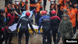 Rescue workers carry the body of a victim recovered during a search and rescue operation near an underpass that has been submerged by a flooded river caused by torrential rains in Cheongju, South Korea, July 16, 2023.