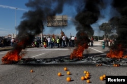 Spanish farmers stand near fire, as they block access to the Castellon port during a protest against high costs, bureaucracy and competition from non-EU countries, in Castellon, Spain, Feb. 7, 2024.