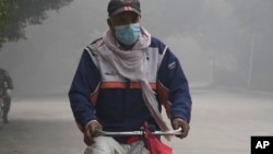 FILE - A cyclist wears mask to head to his work-point as smog envelops the areas of Lahore, Pakistan, Nov. 8, 2023. 