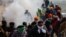 Farmers, who are marching towards New Delhi to press for better crop prices, run for cover amidst tear gas fired by police to disperse them at Shambhu barrier, a border crossing between Punjab and Haryana states, India, Feb. 21, 2024.