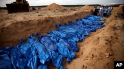 FILE - Palestinians pray over the bodies of people killed in an Israeli bombardment before burying them in a mass grave in Khan Younis, southern Gaza Strip, Nov. 22, 2023.