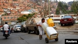 Un hombre empuja barriles llenos de agua en Petare, Venezuela. 