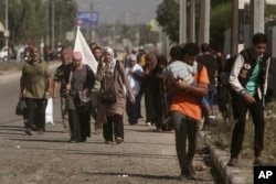 A woman carries a white flag to prevent being shot, as Palestinians flee Gaza City to the southern Gaza Strip on Salah al-Din street in Bureij, Nov. 7, 2023.